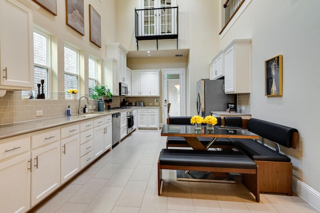 354 Loma Alta Dr, Flower Mound, TX 75022 - kitchen with stainless steel appliances, decorative backsplash, white cabinets, light countertops, and a towering ceiling