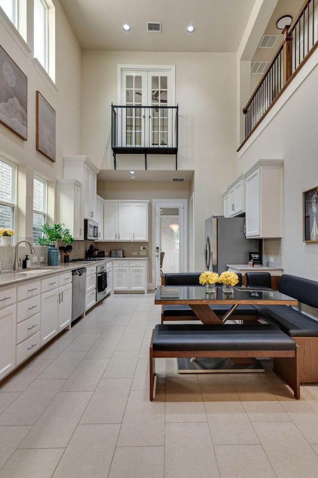 354 Loma Alta Dr, Flower Mound, TX 75022 - kitchen with a high ceiling, stainless steel appliances, tasteful backsplash, white cabinets, and recessed lighting