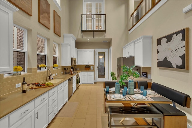 354 Loma Alta Dr, Flower Mound, TX 75022 - kitchen with backsplash, a high ceiling, white cabinets, appliances with stainless steel finishes, and light countertops
