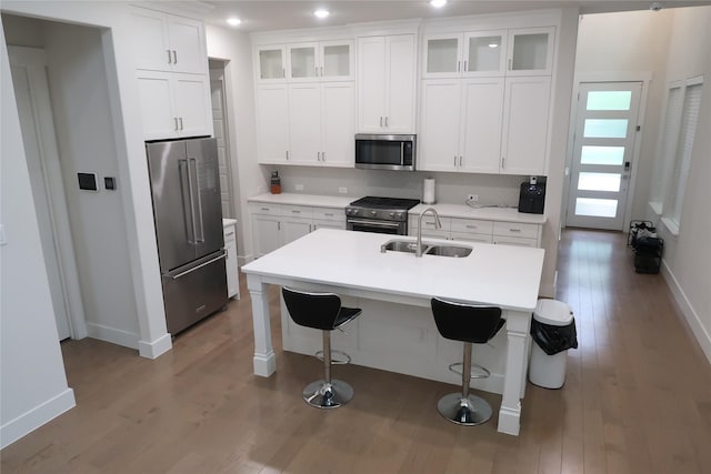 8327 Nunley Ln, Dallas, TX 75231 - kitchen featuring premium appliances, wood finished floors, a breakfast bar area, white cabinetry, and recessed lighting