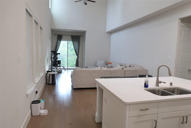 8327 Nunley Ln, Dallas, TX 75231 - kitchen featuring wood finished floors, white cabinets, a ceiling fan, a high ceiling, and light countertops