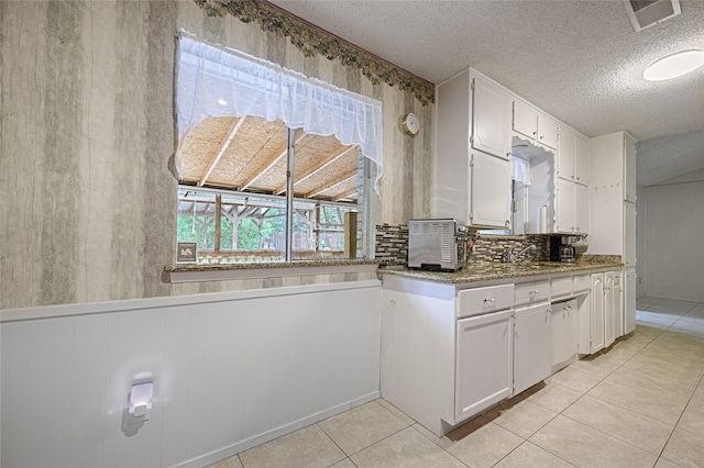 1803 Windsor Dr, Arlington, TX 76012 - kitchen with a textured ceiling, white cabinets, decorative backsplash, light tile patterned flooring, and light stone counters