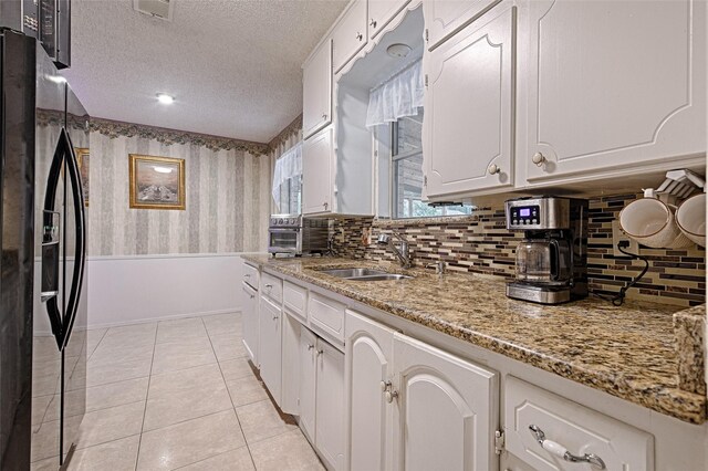 1803 Windsor Dr, Arlington, TX 76012 - kitchen with fridge with ice dispenser, backsplash, white cabinetry, wallpapered walls, and a textured ceiling