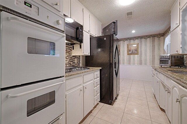 1803 Windsor Dr, Arlington, TX 76012 - kitchen with black appliances, white cabinets, a textured ceiling, backsplash, and light tile patterned flooring