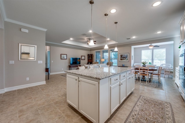 8031 Reservoir Dr, Frisco, TX 75036 - kitchen featuring ornamental molding, ceiling fan, open floor plan, a kitchen island, and white cabinetry