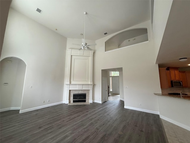 14641 Turnbridge Dr, Frisco, TX 75035 - unfurnished living room with wood finished floors, ceiling fan, a fireplace, arched walkways, and a high ceiling
