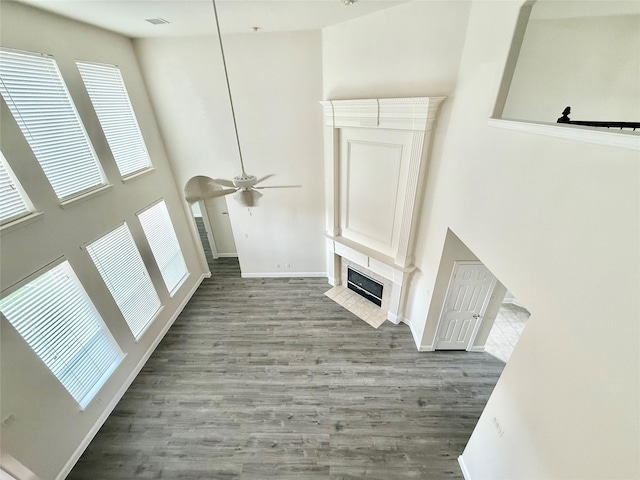 14641 Turnbridge Dr, Frisco, TX 75035 - unfurnished living room with wood finished floors, a ceiling fan, a fireplace, and a high ceiling