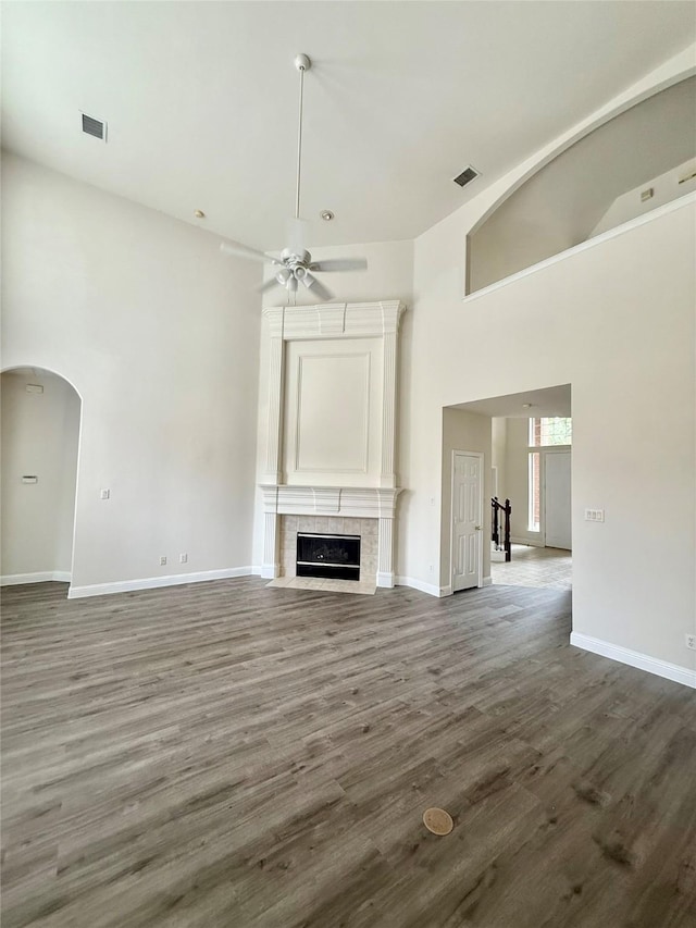 14641 Turnbridge Dr, Frisco, TX 75035 - unfurnished living room with a towering ceiling, a fireplace with flush hearth, ceiling fan, dark wood finished floors, and arched walkways