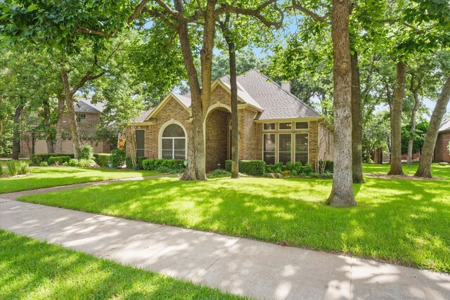 3102 Hidden Springs Dr, Corinth, TX 76210 - traditional-style house featuring brick siding, a front yard, a shingled roof, and a chimney