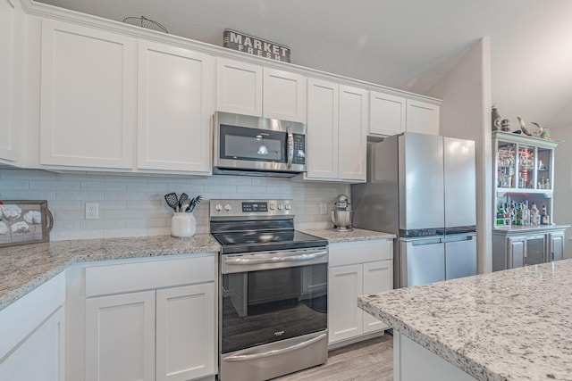 656 Bunk House Dr, Venus, TX 76084 - kitchen featuring appliances with stainless steel finishes, white cabinets, backsplash, light wood-type flooring, and light stone countertops