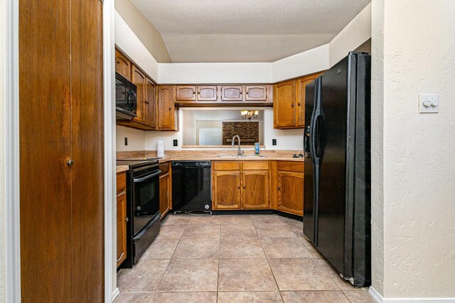 2114 Norway Dr, Garland, TX 75040 - kitchen with black appliances, a textured wall, brown cabinets, light countertops, and light tile patterned floors