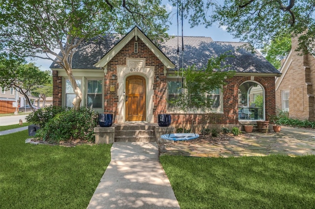 6201 Reiger Ave, Dallas, TX 75214 - tudor house with brick siding, a front yard, and roof with shingles