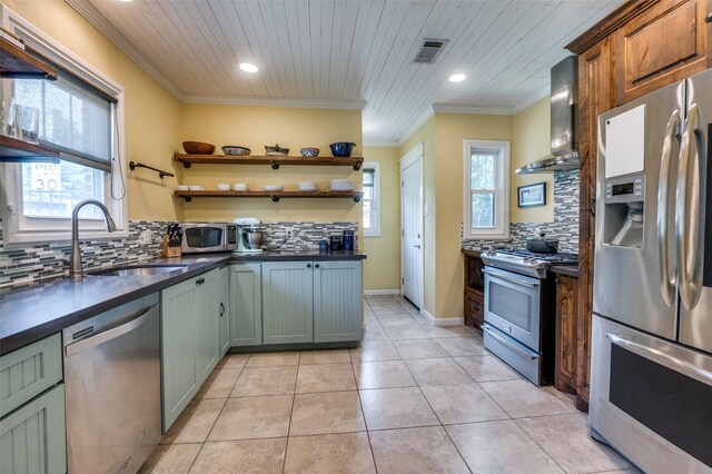6201 Reiger Ave, Dallas, TX 75214 - kitchen featuring stainless steel appliances, wall chimney range hood, dark countertops, backsplash, and crown molding