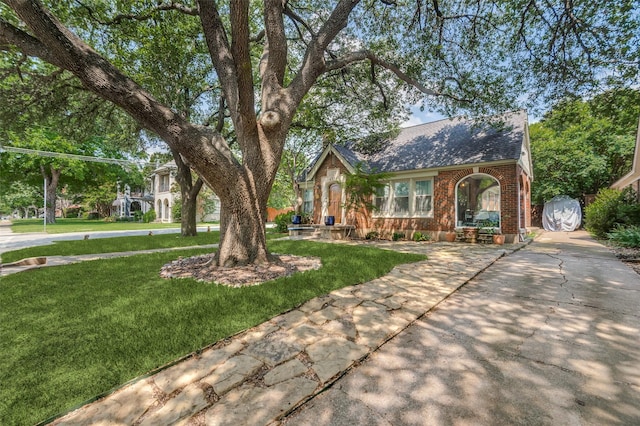 6201 Reiger Ave, Dallas, TX 75214 - tudor-style house with brick siding, a front yard, and roof with shingles