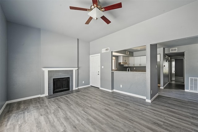 2415 Sunflower Dr, Arlington, TX 76014 - unfurnished living room featuring dark wood-style floors, ceiling fan, high vaulted ceiling, and a tiled fireplace