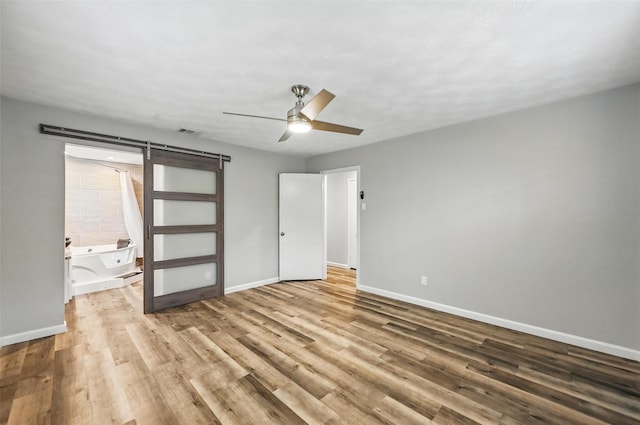 8434 Sweetwood Dr, Dallas, TX 75228 - unfurnished bedroom with wood finished floors, a ceiling fan, and a barn door