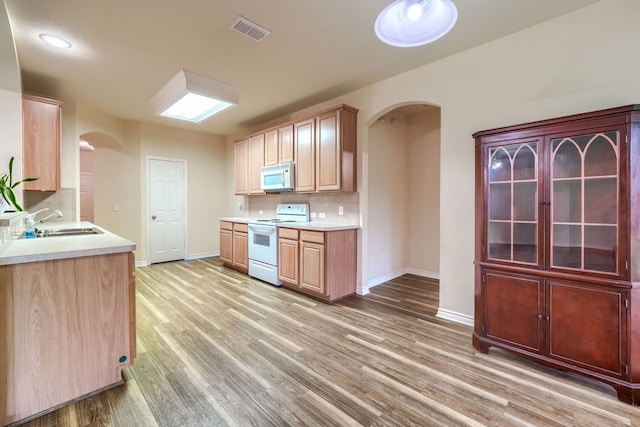 3003 Margot Ct, Wylie, TX 75098 - kitchen featuring white appliances, arched walkways, decorative backsplash, and light wood-style flooring