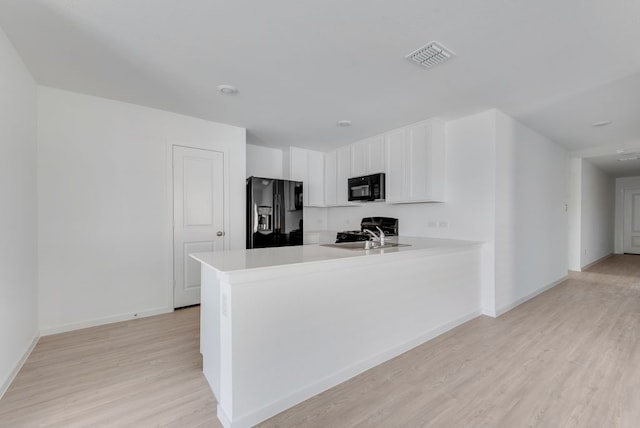 1961 Kiwi Dr, Royse City, TX 75189 - kitchen with black appliances, light wood-type flooring, a peninsula, white cabinets, and light countertops