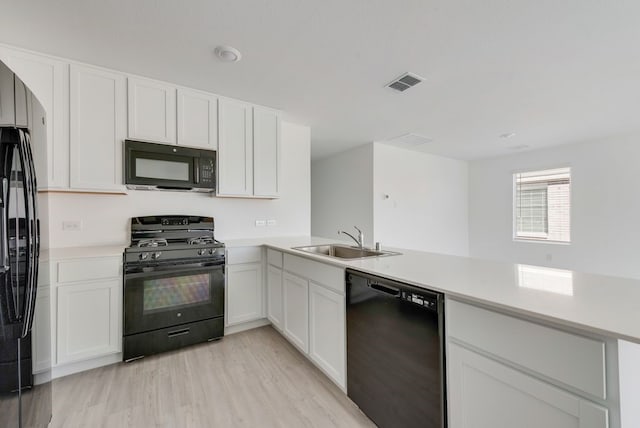 1961 Kiwi Dr, Royse City, TX 75189 - kitchen featuring black appliances, light countertops, light wood finished floors, white cabinetry, and a peninsula