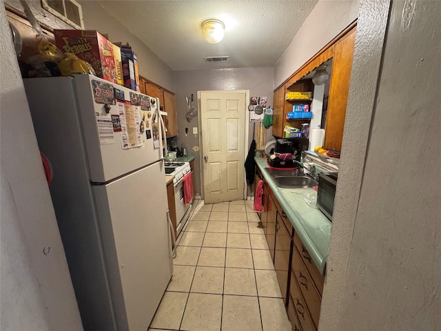 2643 Hillsboro Ave, Dallas, TX 75228 - kitchen with white appliances, brown cabinets, light tile patterned flooring, light countertops, and a textured ceiling