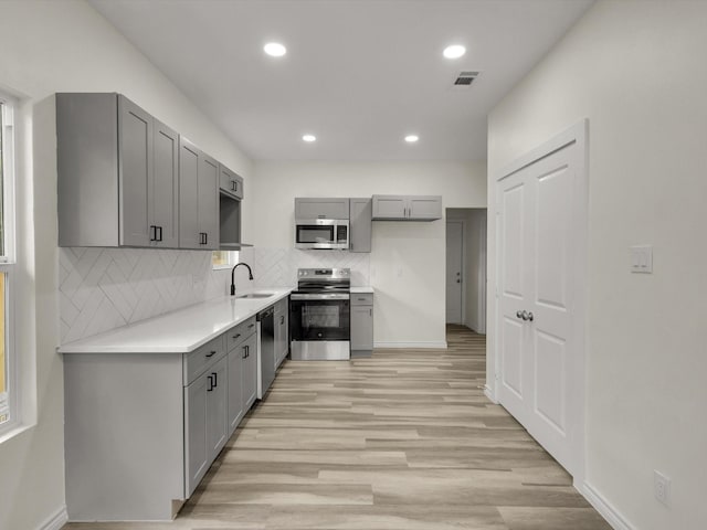 3526 Elsie Faye Heggins St, Dallas, TX 75210 - kitchen with appliances with stainless steel finishes, gray cabinetry, backsplash, recessed lighting, and light wood-style floors