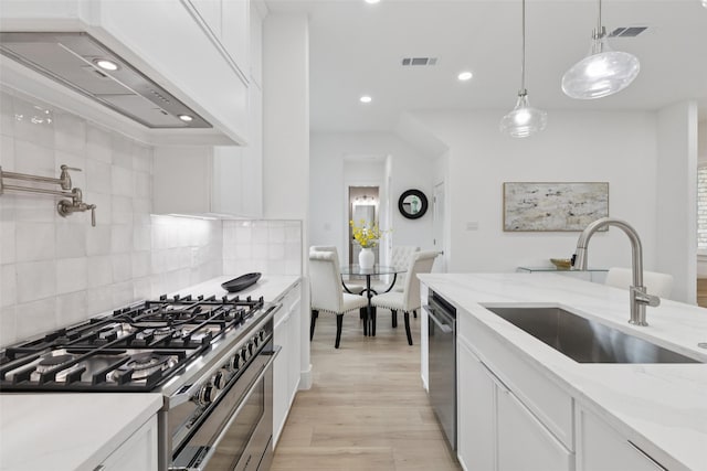 1000 W 10th St, Dallas, TX 75208 - kitchen featuring appliances with stainless steel finishes, premium range hood, white cabinets, light wood-type flooring, and backsplash