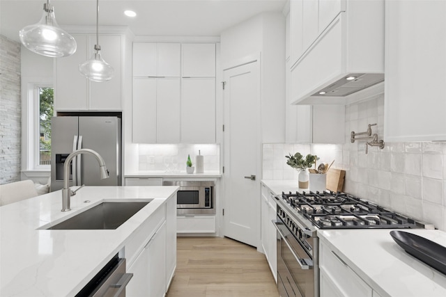 1000 W 10th St, Dallas, TX 75208 - kitchen featuring appliances with stainless steel finishes, custom range hood, white cabinetry, light wood-style floors, and backsplash