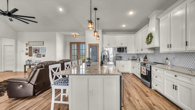 1401 County Road 1470, Chico, TX 76431 - kitchen featuring stainless steel appliances, open floor plan, a breakfast bar, backsplash, and light wood finished floors