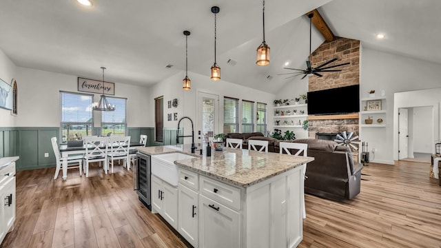 1401 County Road 1470, Chico, TX 76431 - kitchen featuring wine cooler, a fireplace, a wainscoted wall, white cabinets, and beam ceiling