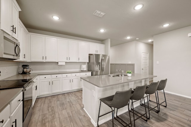 3018 Dakota Trl, Crandall, TX 75114 - kitchen with appliances with stainless steel finishes, decorative backsplash, light wood-style flooring, a breakfast bar area, and recessed lighting