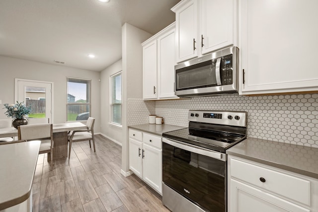 3018 Dakota Trl, Crandall, TX 75114 - kitchen with appliances with stainless steel finishes, decorative backsplash, white cabinets, light wood finished floors, and recessed lighting