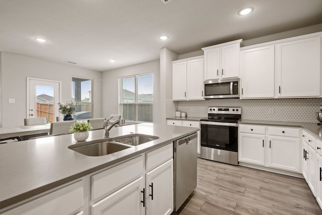 3018 Dakota Trl, Crandall, TX 75114 - kitchen with appliances with stainless steel finishes, decorative backsplash, white cabinetry, recessed lighting, and light wood-style flooring