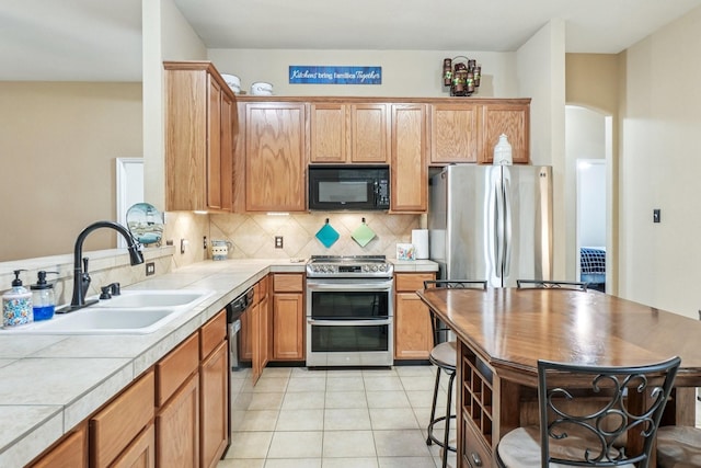 1323 Canyon Creek Rd, Wylie, TX 75098 - kitchen featuring stainless steel appliances, tile counters, decorative backsplash, light tile patterned floors, and arched walkways