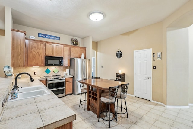 1323 Canyon Creek Rd, Wylie, TX 75098 - kitchen with appliances with stainless steel finishes, backsplash, a breakfast bar, and light tile patterned floors