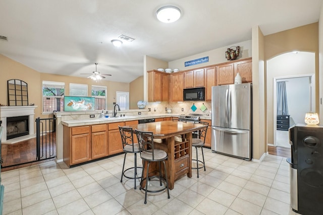 1323 Canyon Creek Rd, Wylie, TX 75098 - kitchen featuring stainless steel appliances, a peninsula, ceiling fan, decorative backsplash, and light countertops