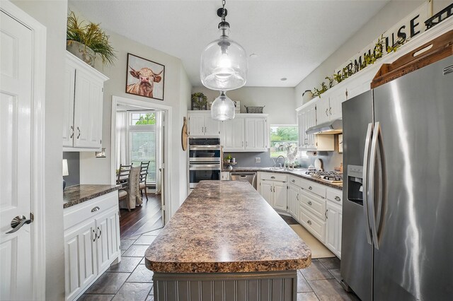 7104 Harlan Dr, Rockwall, TX 75087 - kitchen with stainless steel appliances, plenty of natural light, dark countertops, and white cabinetry