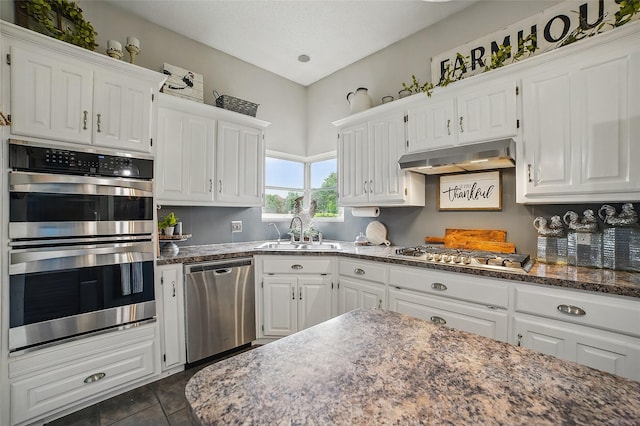 7104 Harlan Dr, Rockwall, TX 75087 - kitchen with appliances with stainless steel finishes, under cabinet range hood, white cabinets, and dark stone counters