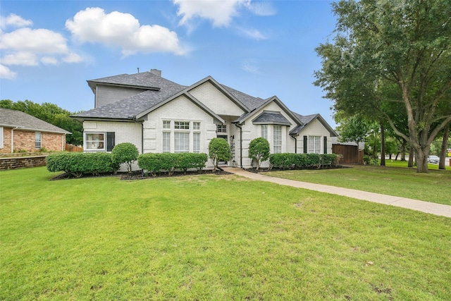 7104 Harlan Dr, Rockwall, TX 75087 - view of front facade with a front lawn, brick siding, a shingled roof, and a chimney