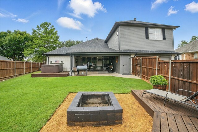 7104 Harlan Dr, Rockwall, TX 75087 - back of property with a hot tub, an outdoor fire pit, a fenced backyard, a patio area, and a wooden deck