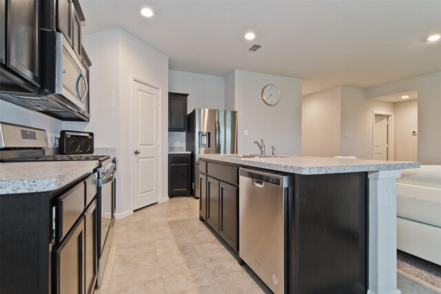 941 Loomis Trl, Justin, TX 76247 - kitchen with stainless steel appliances, a center island with sink, light countertops, recessed lighting, and light tile patterned flooring