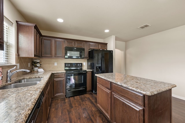 6524 Sheridan Cir, Arlington, TX 76017 - kitchen featuring black appliances, dark wood-style floors, a center island, tasteful backsplash, and light stone countertops