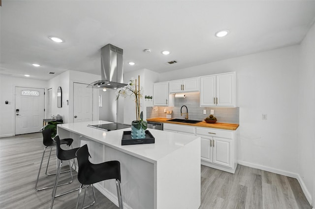 3105 Dupree St, Irving, TX 75062 - kitchen featuring island range hood, white cabinetry, a breakfast bar, light wood-type flooring, and recessed lighting