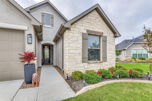 8509 Cocobolo Dr, Denton, TX 76207 - doorway to property featuring stone siding, a lawn, a garage, and stucco siding