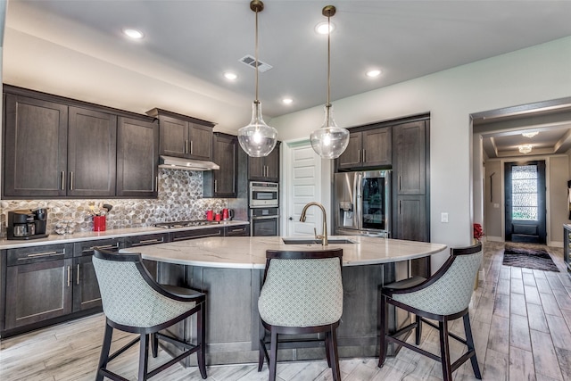 8509 Cocobolo Dr, Denton, TX 76207 - kitchen featuring stainless steel appliances, dark brown cabinets, tasteful backsplash, light wood finished floors, and recessed lighting