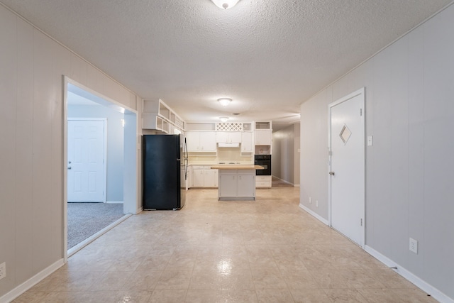 5905 Wheaton Dr, Fort Worth, TX 76133 - kitchen featuring black appliances, under cabinet range hood, a textured ceiling, white cabinets, and a kitchen island