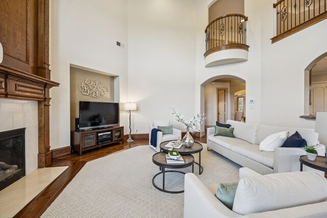 211 Tanner Creek Cir, Sunnyvale, TX 75182 - living room featuring wood finished floors, arched walkways, a high ceiling, and a premium fireplace