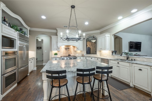917 Stone Cottage Ln, Mckinney, TX 75069 - kitchen with arched walkways, built in appliances, white cabinetry, backsplash, and dark wood-style floors
