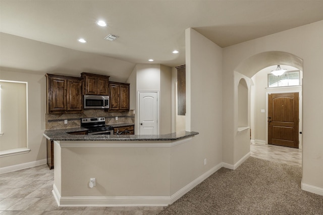 1701 Fair Oaks Ln, Royse City, TX 75189 - kitchen featuring stainless steel appliances, arched walkways, dark stone counters, dark brown cabinetry, and recessed lighting