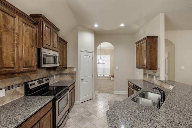 1701 Fair Oaks Ln, Royse City, TX 75189 - kitchen featuring stainless steel appliances, arched walkways, stone counters, light tile patterned flooring, and recessed lighting