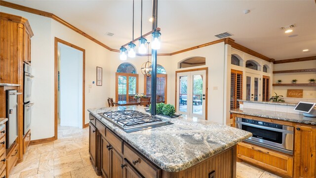10133 Leaping Buck Pt, Fort Worth, TX 76126 - kitchen with stainless steel appliances, ornamental molding, a kitchen island, brown cabinetry, and light stone counters
